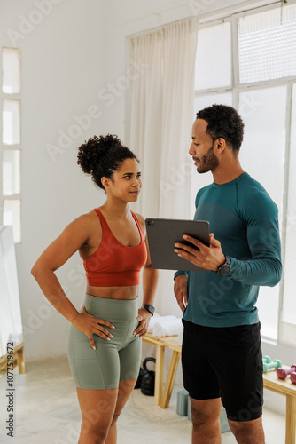 Personal trainer showing digital tablet to client at the gym photo