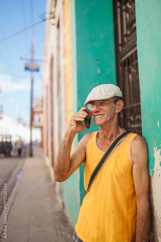 Cuban man talking on the phone by colorful wall Cuban man talking on the phone by colorful wall
