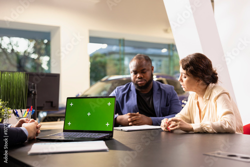 Salesperson using isolated screen notebook, applying sales tactic to persuade clients to make purchase. Sales executive using chroma key laptop encouraging customers to buy extra vehicle warranty photo