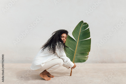 Calm lady with green leaf at wall photo