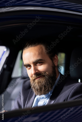 Portrait of smiling client in car showroom checking automobile features during test drive, comparing models. Cheerful man driving vehicle, satisfied with autonomy, looking to make informed purchase photo