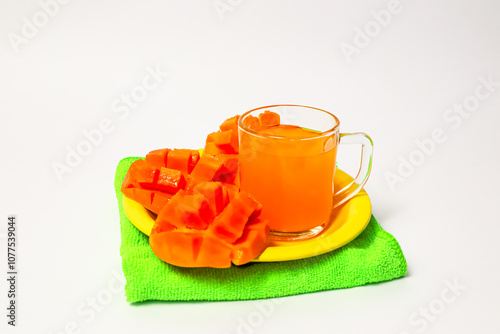 Mango juice and mango slices on a yellow plate, top view