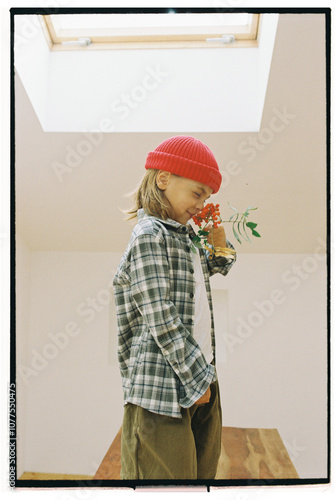 A joyful child in a red cap holds a rowan branch in his hands photo