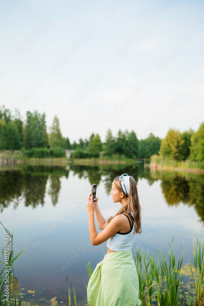 A woman takes pictures of a lake A woman takes pictures of a lake