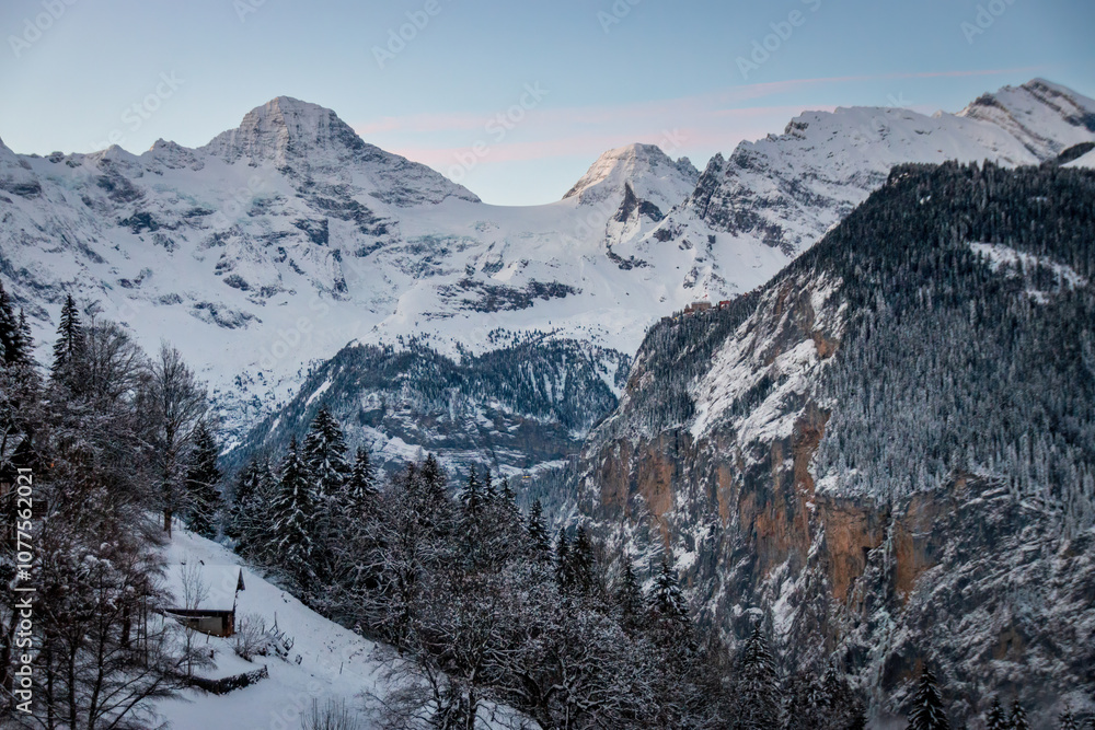Scenic view of Lauterbrunnen Valley, Switzerland seen from Wengen with snowcovered mountains with Breithorn (left) and Tschingelhorn (right) in winter against blue sky at sunset