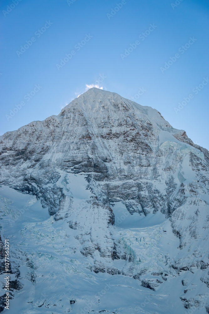Scenic view of snowcovered Mönch mountain in Switzerland early in the morning against blue sky
