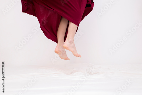 Woman jumping on bed with red dress photo