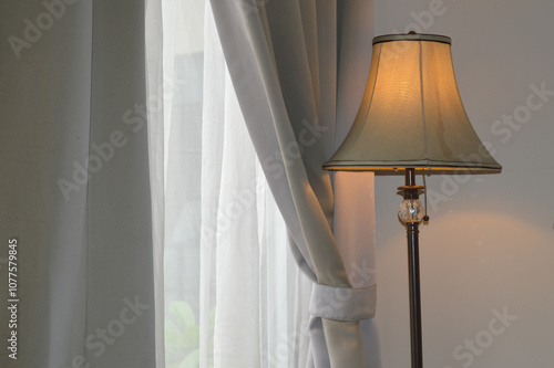 a lamp stand against a gray window curtain interior in a hotel photo