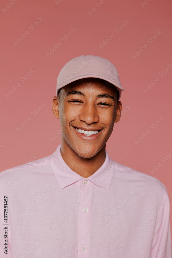 Man wearing pink shirt and cap smiling on pink background Man wearing pink shirt and cap smiling on pink background