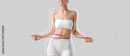 Beautiful young happy sporty woman with measuring tape on grey background, cl...