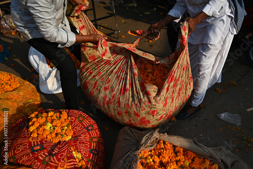 Vendors tie up flower bundles at a market in India photo