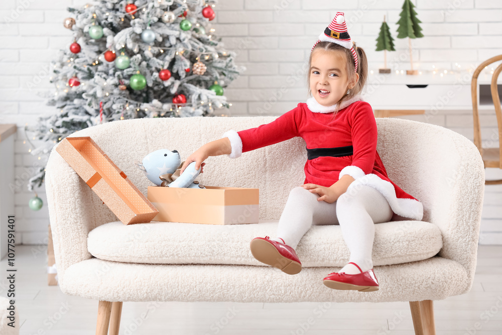 Cute little girl in Santa costume with gift box at home on Christmas eve Cute little girl in Santa costume with gift box at home on Christmas eve