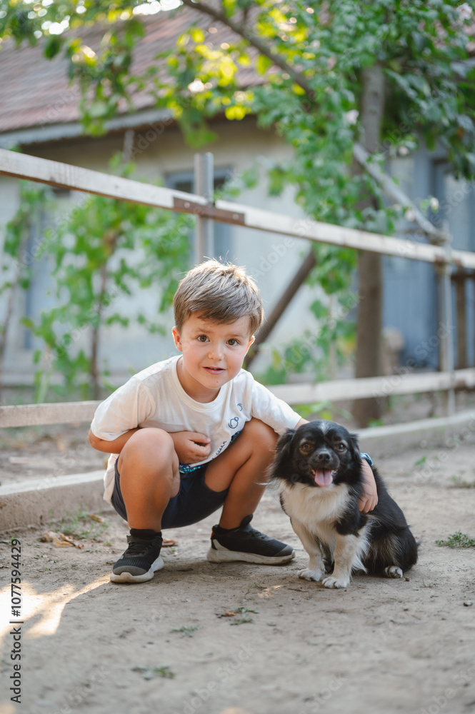 Young boy crouching next to a playful dog outdoors Young boy crouching next to a playful dog outdoors
