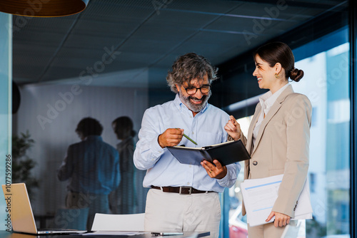 Businesspeople having informal meeting reading notes in notebook