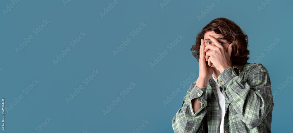 Anxiety and stress concept. Curly guy closing his face in fear on color background Anxiety and stress concept. Curly guy closing his face in fear on color background