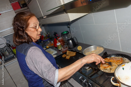 Grandmother cooking crispy milanesas in the kitchen photo