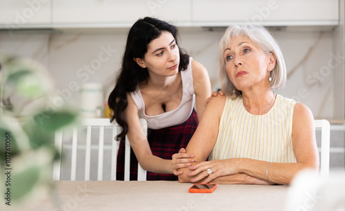 Adult daughter apologizes to her elderly mother after a domestic quarrel