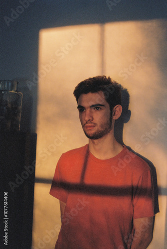 Serious film portrait of teen boy standing with sun and shadow photo