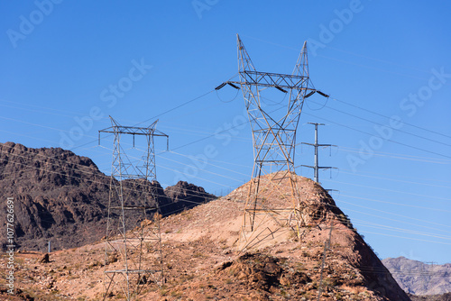 Transmission power lines at mid-day on the red plateaus of the American Southwest. Full sun, clear, blue sky.