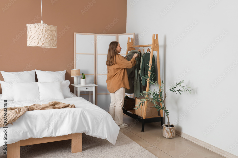 Pretty young woman choosing clothes in modern bedroom Pretty young woman choosing clothes in modern bedroom