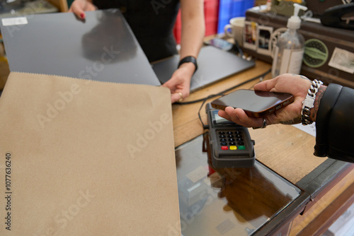 Customer making a contactless payment with phone in a record store photo