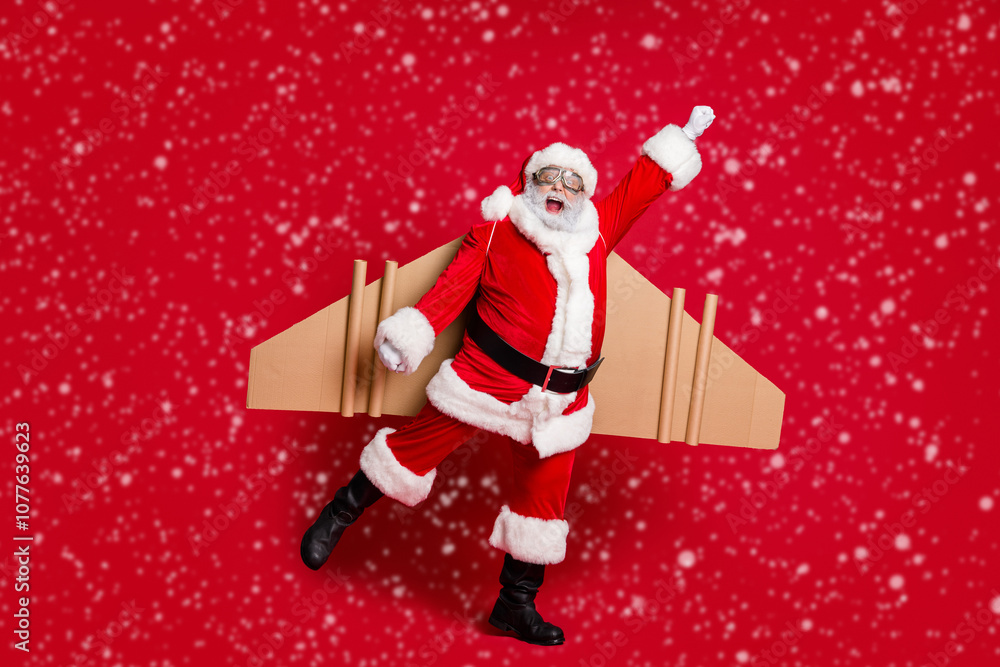 Full length photo of retired infantile grandpa white beard jetpack raise fist pretend superhuman fly around earth wear santa x-mas costume coat spectacles cap isolated red color background Full length photo of retired infantile grandpa white beard jetpack raise fist pretend superhuman fly around earth wear santa x-mas costume coat spectacles cap isolated red color background