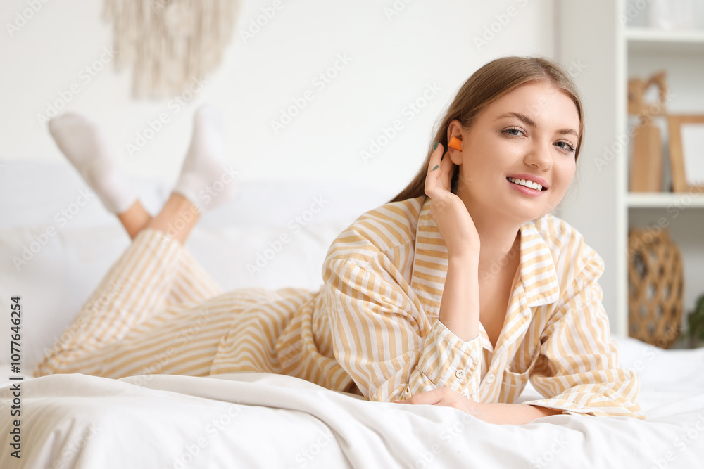Young woman with earplugs lying in bedroom Young woman with earplugs lying in bedroom