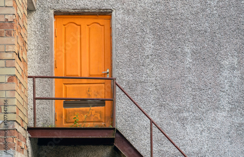 Old abandoned orange door with iron stairs and copy space photo