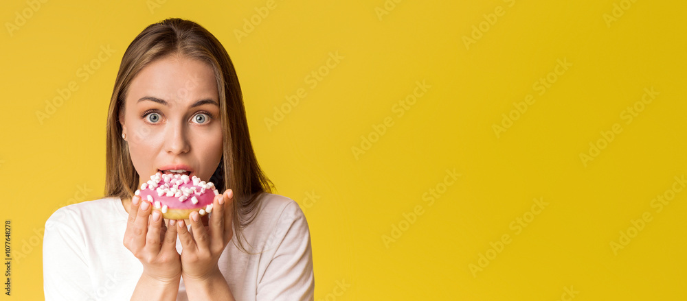 Cheat Meal. Young Lady Biting Tasty Donut, Posing Over Yellow Background In Studio And Looking At Camera, Free Space Cheat Meal. Young Lady Biting Tasty Donut, Posing Over Yellow Background In Studio And Looking At Camera, Free Space