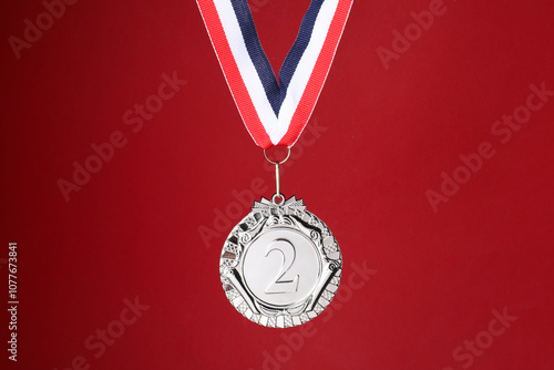 Silver medal with striped ribbon on red background