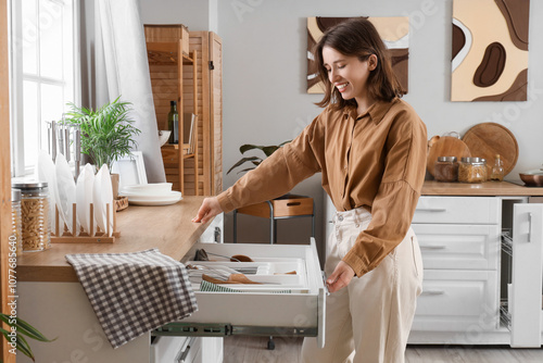 Young woman opening drawer in kitchen