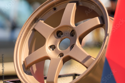 Close-up of Bronze Car Alloy Wheel on Display Outdoors photo