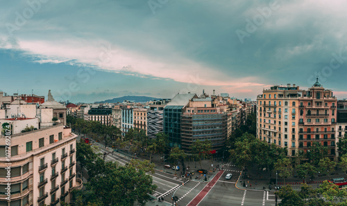 Aerial view of passeig de gracia, a prominent street in barcelona, featuring diverse architectural styles, bustling intersections, and a cloudy sky creating a dramatic urban landscape photo