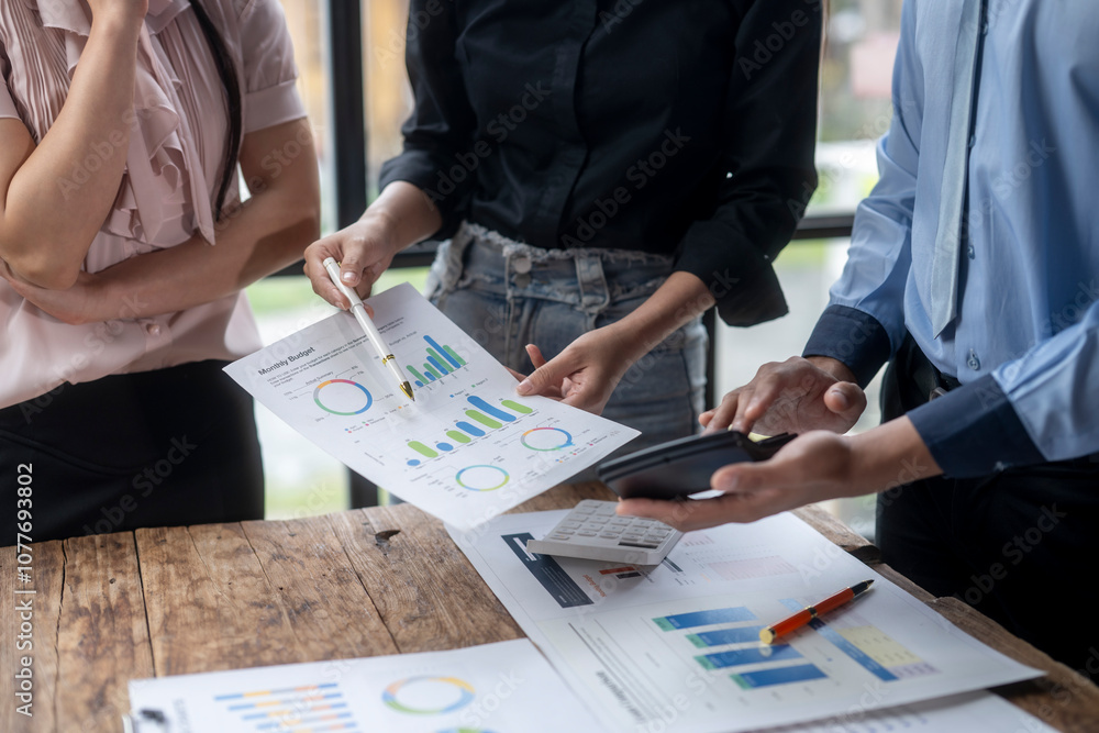 A group of people are looking at graphs and charts on a table A group of people are looking at graphs and charts on a table