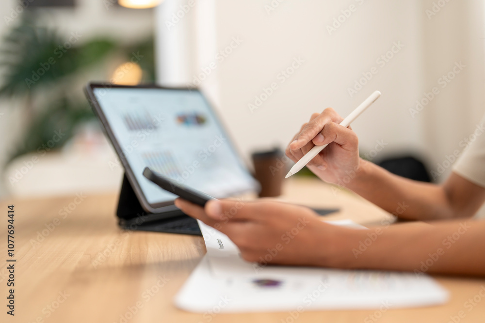 Fototapeta premium Businesswoman analyzing financial data on tablet and smartphone using stylus