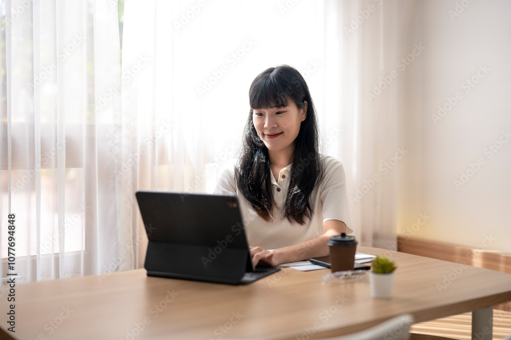 Young asian woman working from home using tablet computer Young asian woman working from home using tablet computer