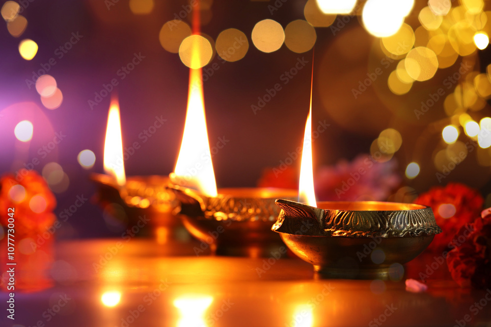 Diwali celebration. Diya lamps and beautiful flowers on color background, closeup. Bokeh effect Diwali celebration. Diya lamps and beautiful flowers on color background, closeup. Bokeh effect