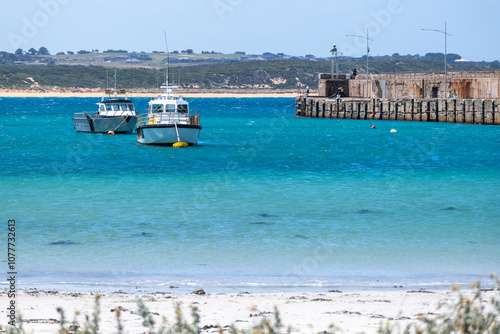 The scenic Warrnambool breakwater and Lady Bay Beach in Victoria, Australia. Boats bob on the clean and turquoise waters in the harbor, with a beautiful sandy beach along the shore. photo