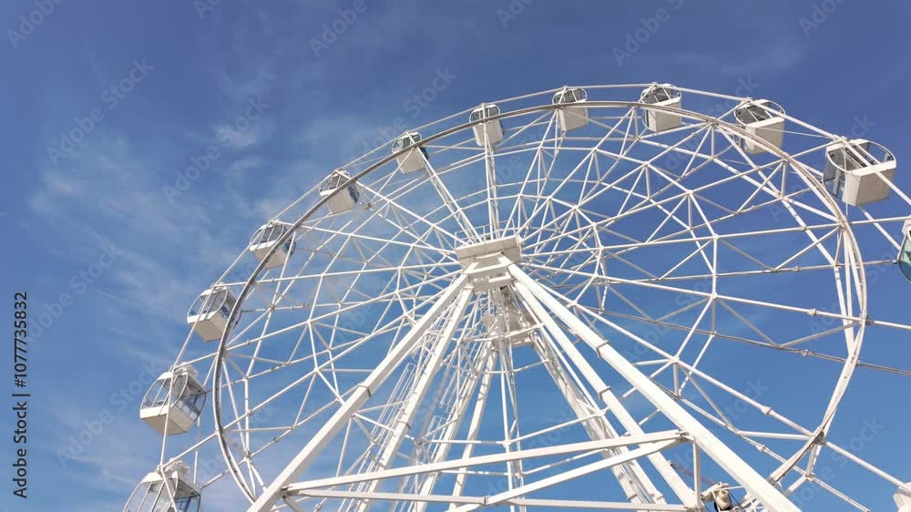 A large white Ferris wheel against a clear blue sky. A large white Ferris wheel against a clear blue sky.