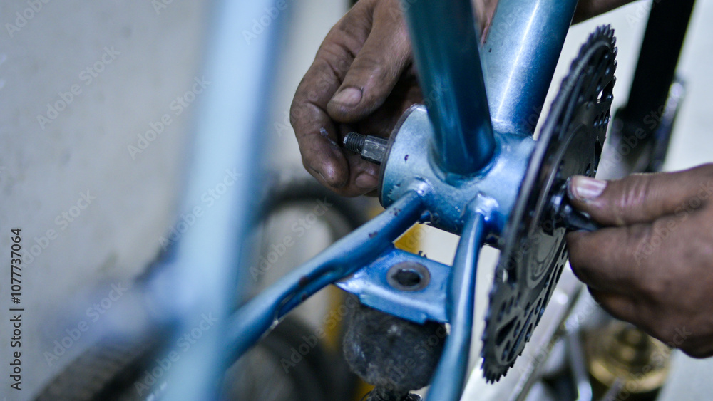 Fototapeta premium Unrecognizable man fixing blue bike in bicycle mechanics workshop