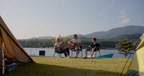 The white people  family with grandparents enjoy playing guitar and music  garden parties gathering camping tents near the lake and relaxing together on the happy time 