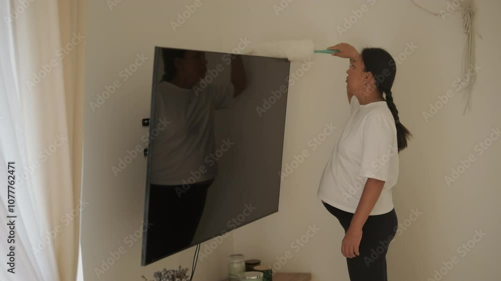 A beautiful pregnant woman tidying her home, engaged in household chores. The scene captures domestic life, maternity, and the balance of routine and preparation during pregnancy A beautiful pregnant woman tidying her home, engaged in household chores. The scene captures domestic life, maternity, and the balance of routine and preparation during pregnancy