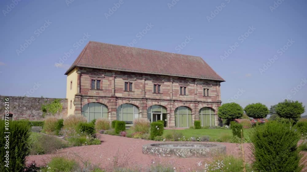 This is a slow-motion shot of the historic Orangery in Blieskastel, featuring traditional architecture and a lush summer landscape. It is a captivating scene of greenery and a blue sky. This is a slow-motion shot of the historic Orangery in Blieskastel, featuring traditional architecture and a lush summer landscape. It is a captivating scene of greenery and a blue sky.