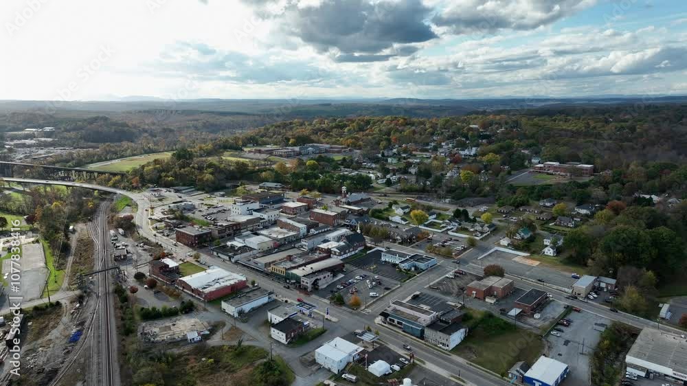 Traffic on Main street of small american town in autumn season.Sunny day with clouds over forest landscape. Tracks of railroad and bridge over river in background. Virginia, America.Aerial wide shot. Traffic on Main street of small american town in autumn season.Sunny day with clouds over forest landscape. Tracks of railroad and bridge over river in background. Virginia, America.Aerial wide shot.
