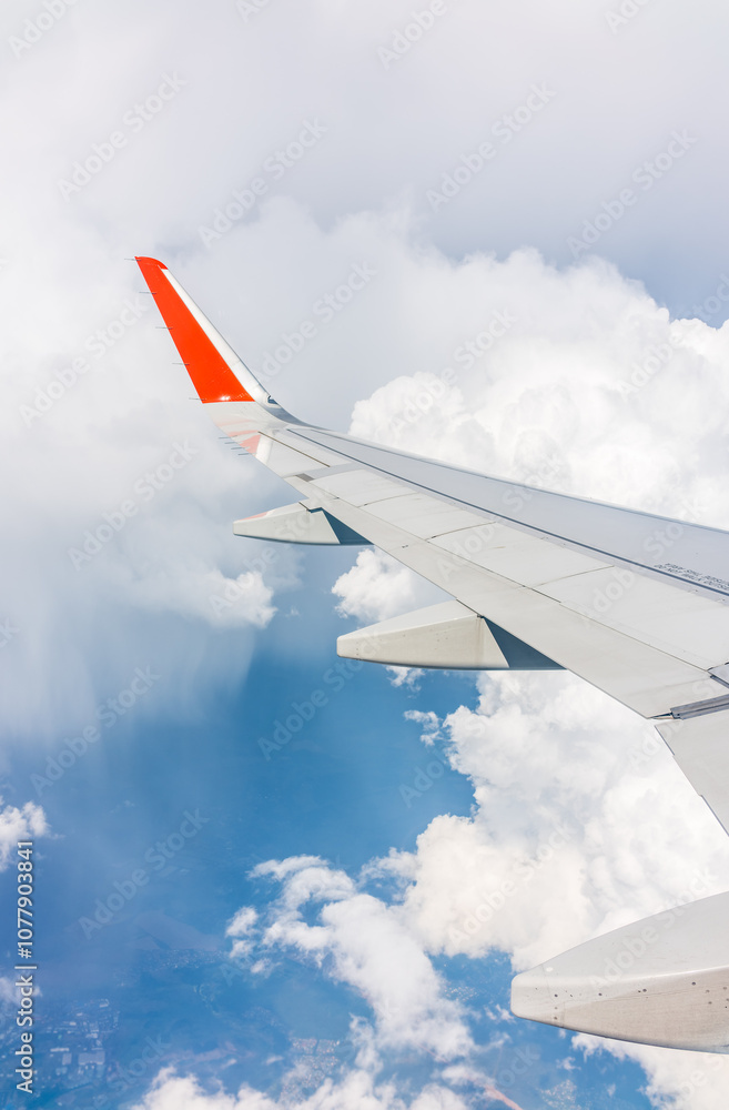 Fototapeta premium View from the airplane window at a beautiful cloudy sky and the airplane wing