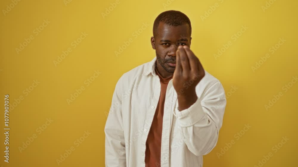 Man, african american, wearing shirt, standing with italian gesture; confident hand and fingers expression over isolated yellow background