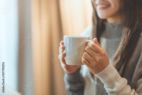 Close up of women's hands holding white cup mug in winter with copy space advertising text message, sweet coffee or tea.