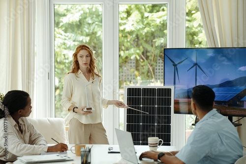 Woman giving presentation of solar battery to her colleagues during teamwork in office