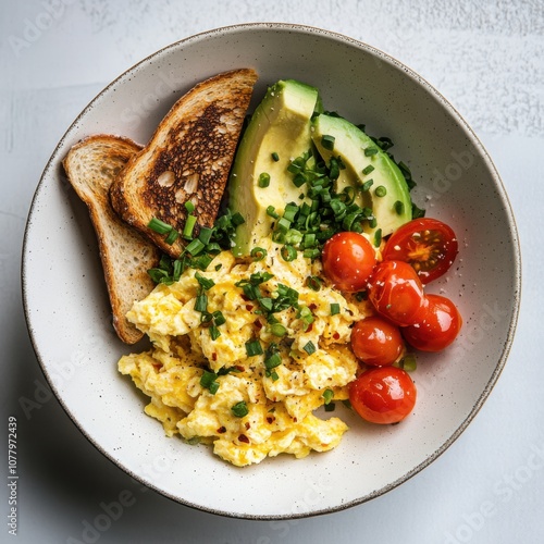 A hearty breakfast bowl with scrambled eggs, avocado slices, and crispy bacon
