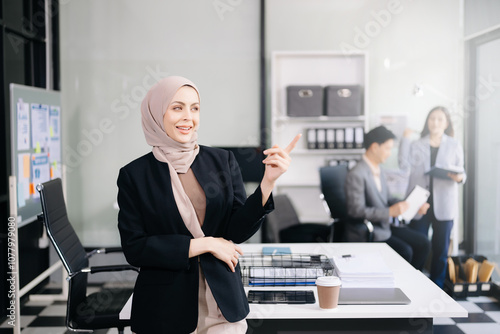 Confident female entrepreneur looking at the camera while standing. Young businesswoman standing in the boardroom